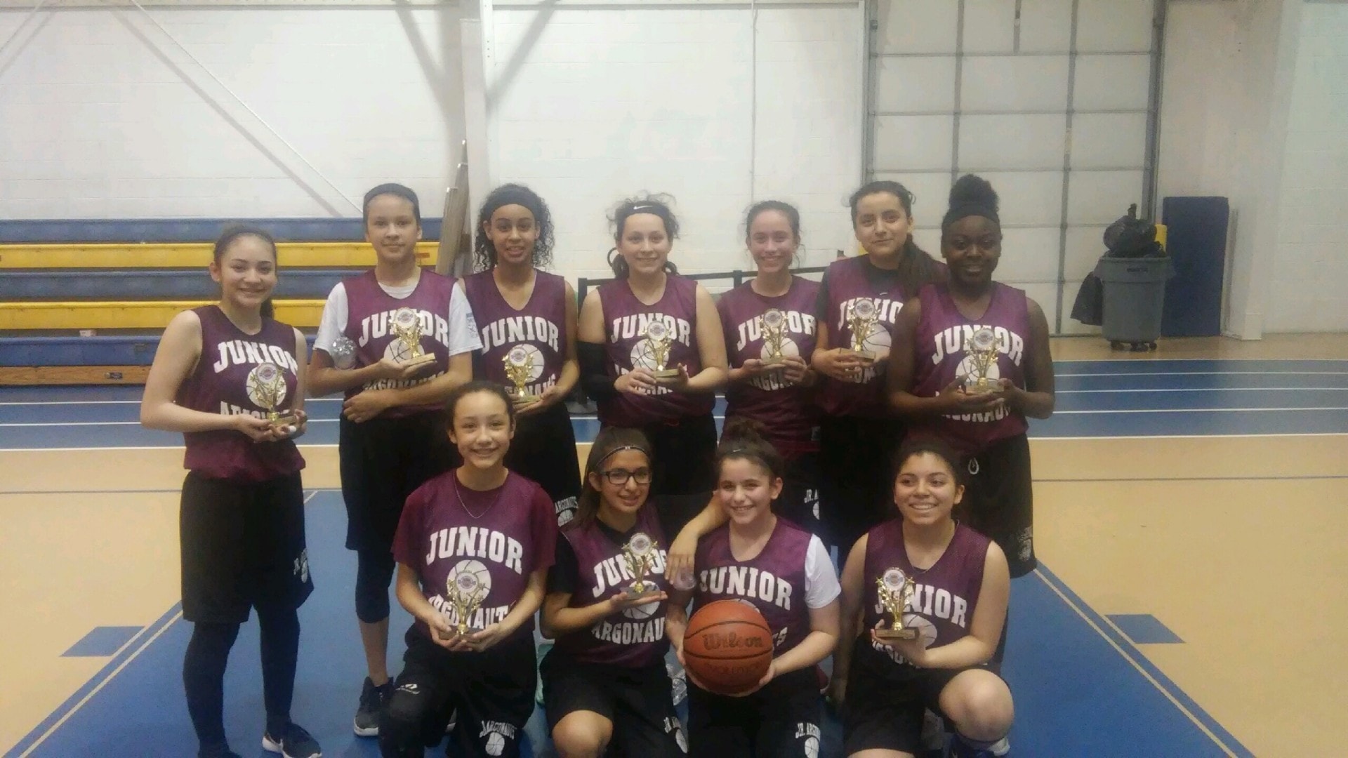 Junior Argonauts team holding trophies on blue court
